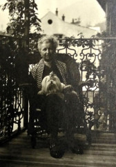 Pia Seidensacher auf einem Balkon sitzend mit Hund auf dem Schoß